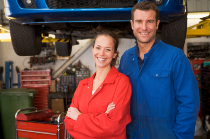 Two mechanics standing in garage smiling Two mechanics standing in garage smiling